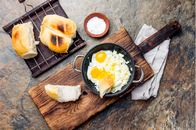 Imagen de un desayuno clásico chileno: huevos revueltos con marraquetas tostadas