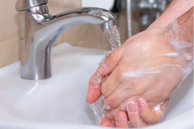 Imagen de una persona que se lava las manos en el lavabo con agua y jabón