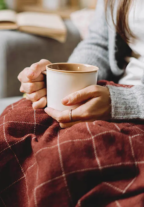 mujer abrigada tomando una taza de te