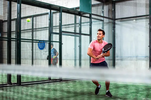 Persona jugando padel en una cancha para mantenerse activo en otoño