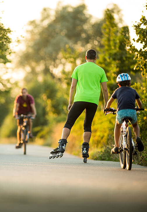 Personas manejando bicicleta y patines en un parque