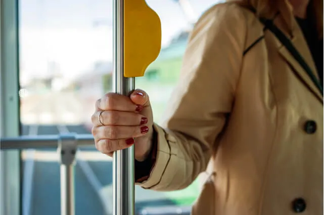 Fotografía de una mujer sosteniendo un poste en el autobús